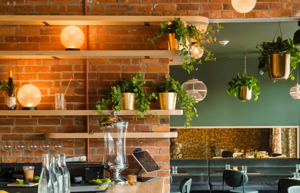 Shelves on the brick wall carry lamps and plants over the banquette.