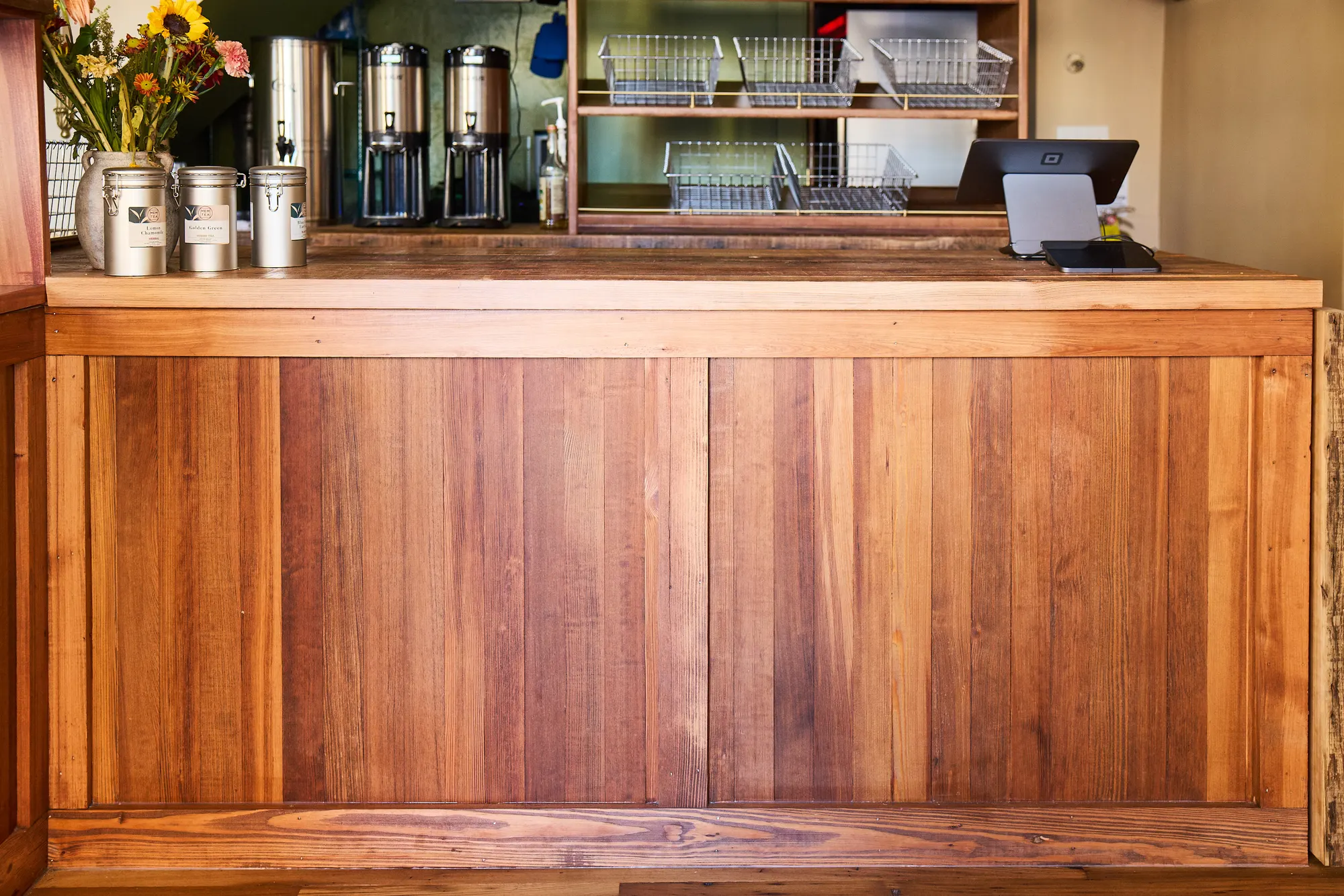 The counter's front in vertical reclaimed boards, with tins, urns and the till on top.
