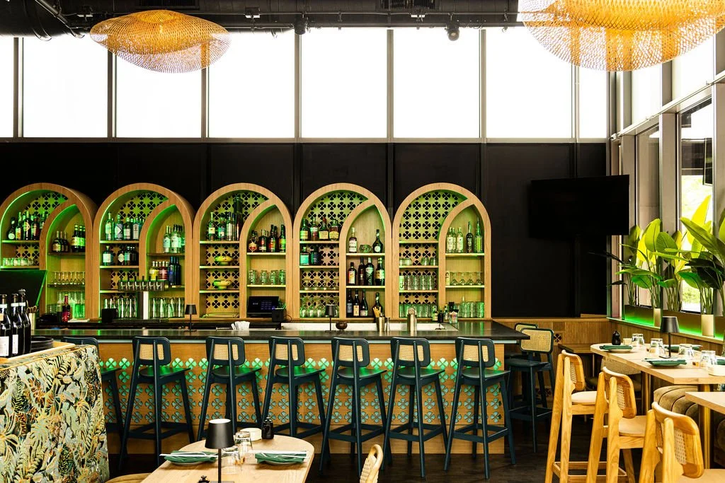The bar at Cocolee, arched niches lit green behind it