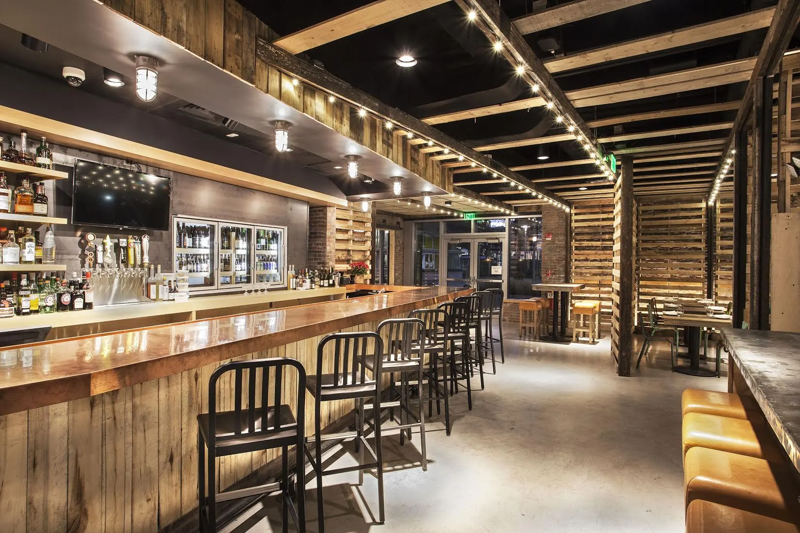 The bar and its stools running the length of the room under a slatted timber ceiling.