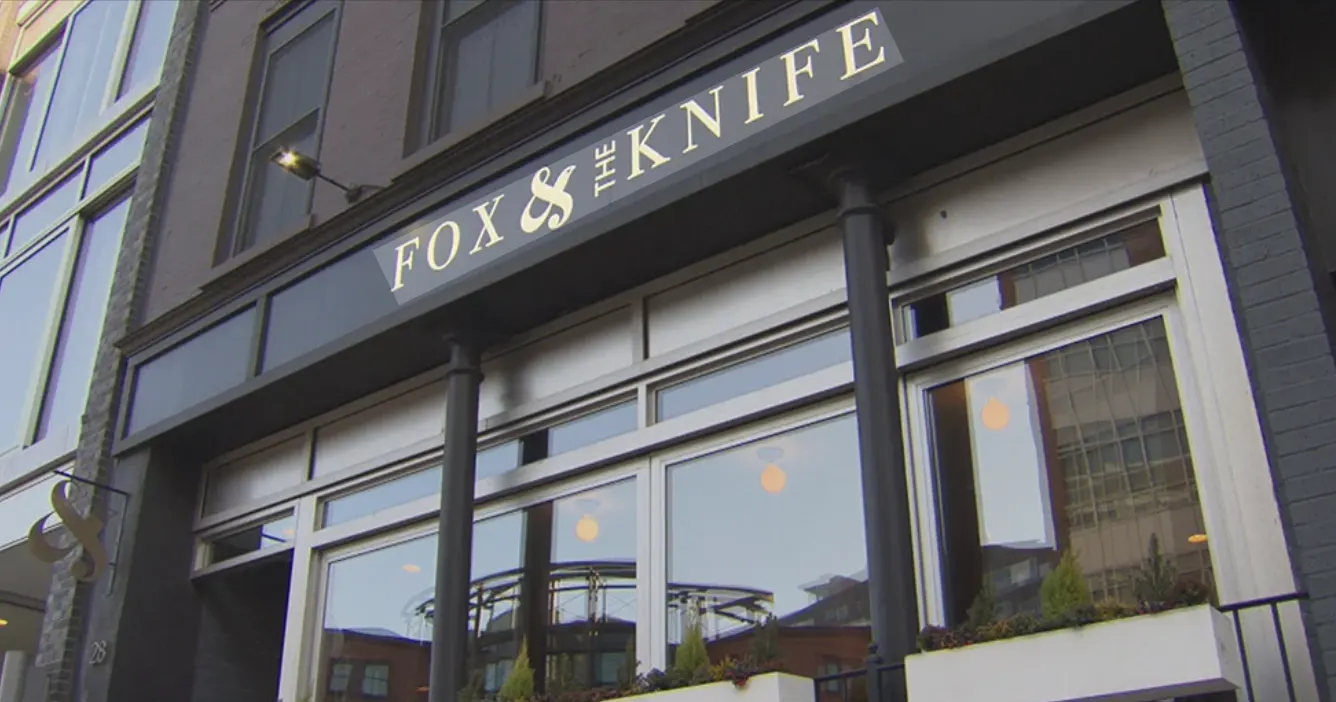 The front of Fox & the Knife: its name in gold on a dark fascia above tall shopfront windows, between black columns