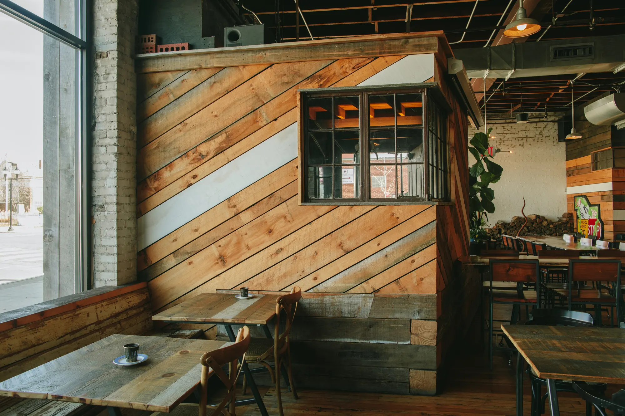 A room within the room, clad in diagonal reclaimed boards with a steel-framed window and a white stripe across it.