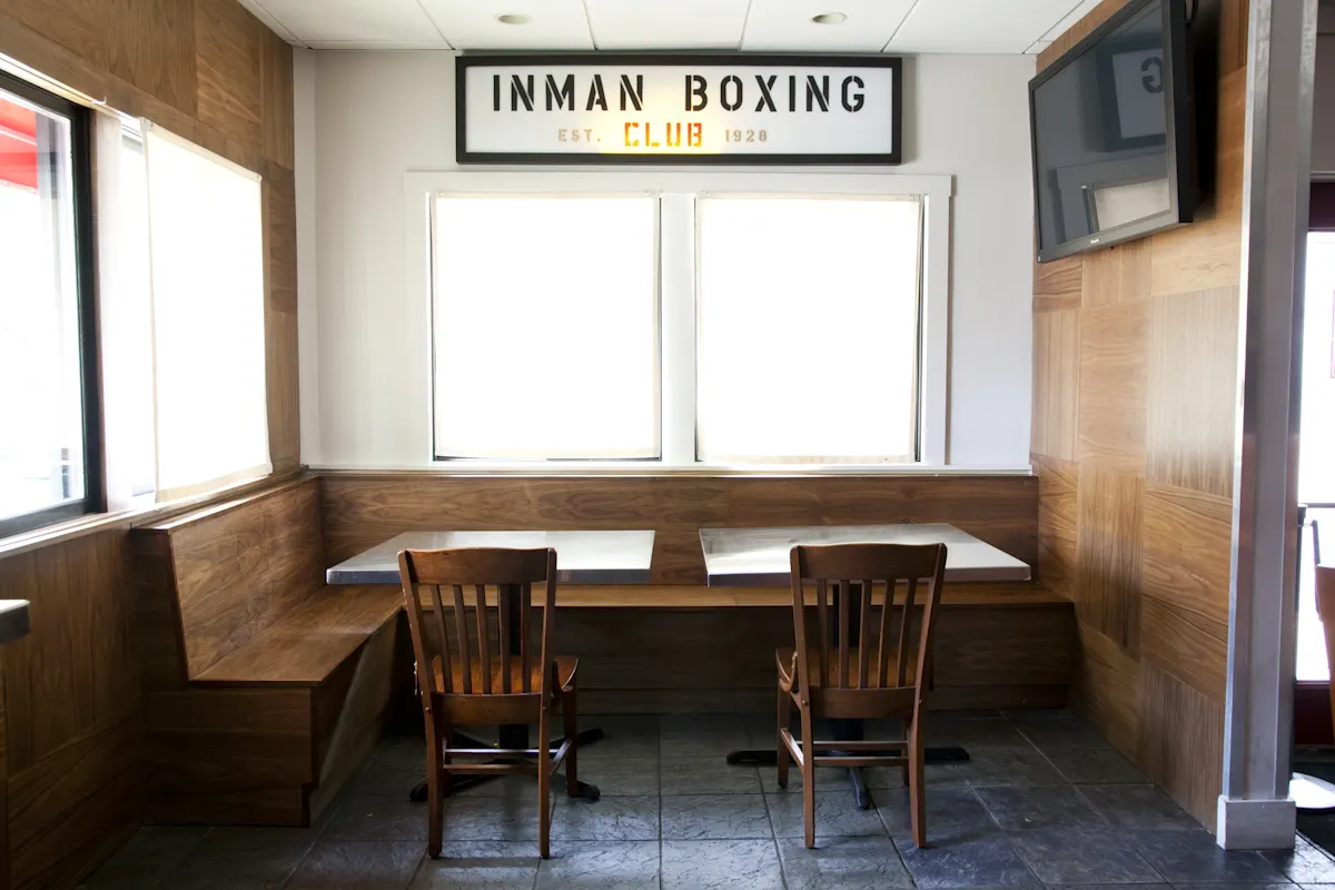 A timber booth by a window under an Inman Boxing Club sign.
