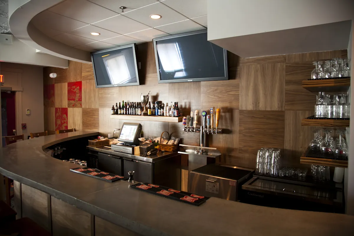 Parlor Sports: a curved bar with televisions above and timber cabinets behind