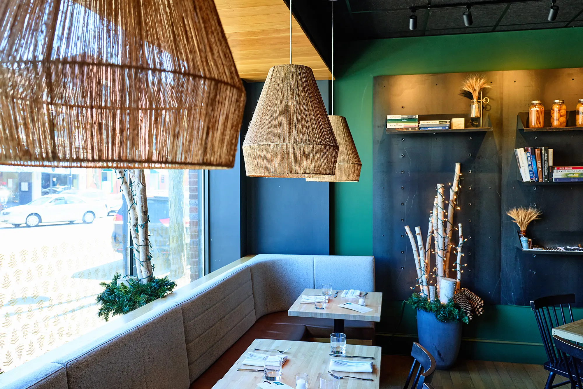 The window banquette and its tables under woven pendants, with the street outside.