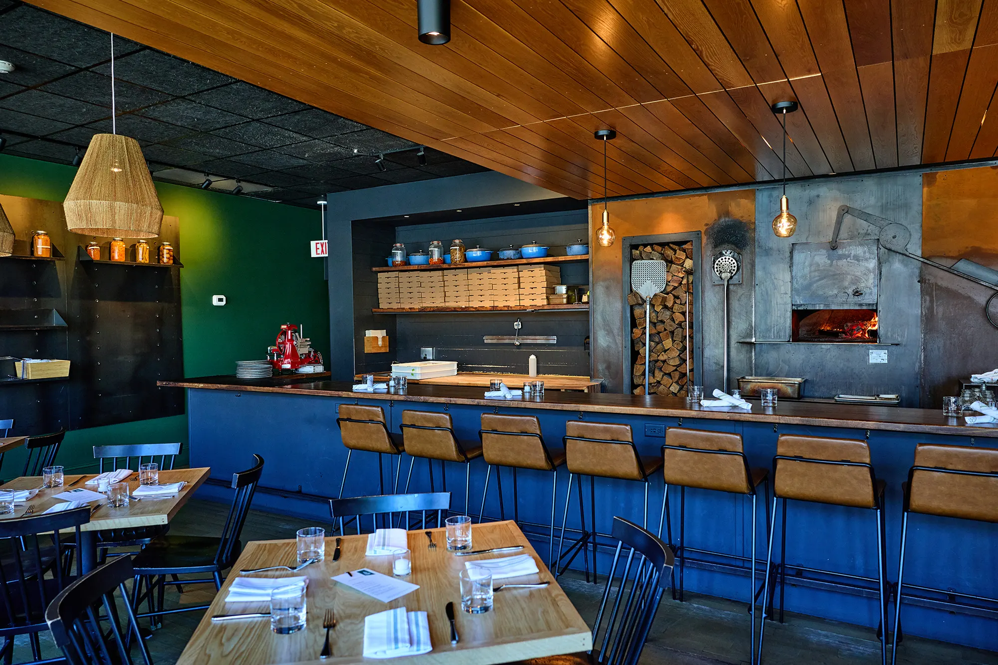 The dining room and the long blue bar, with the oven glowing at the far end.
