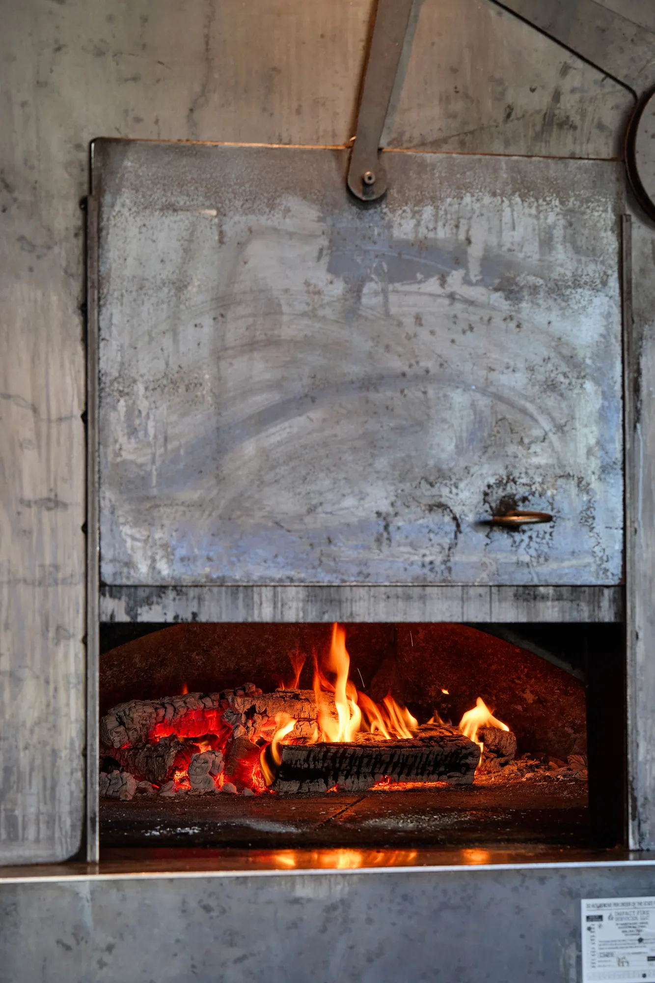Flames in the oven's mouth beneath its steel door.