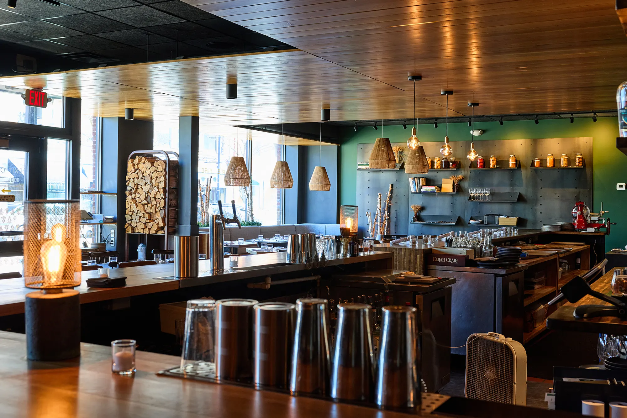 The dining room seen across the bar, with the shelving wall and pendants beyond.