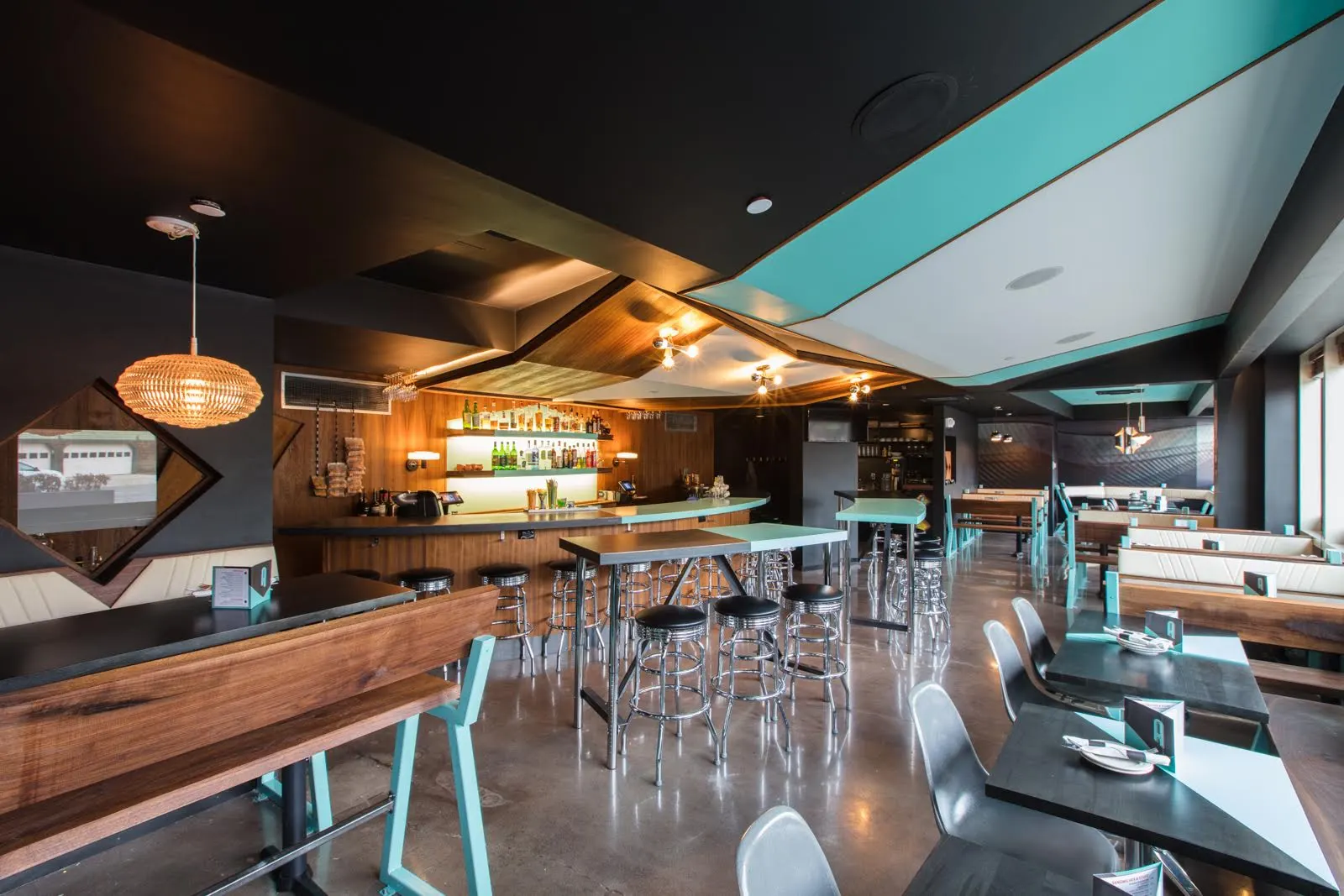 The Automatic: tall tables and stools in front of a timber-lined bar, under a ceiling of teal and white panels