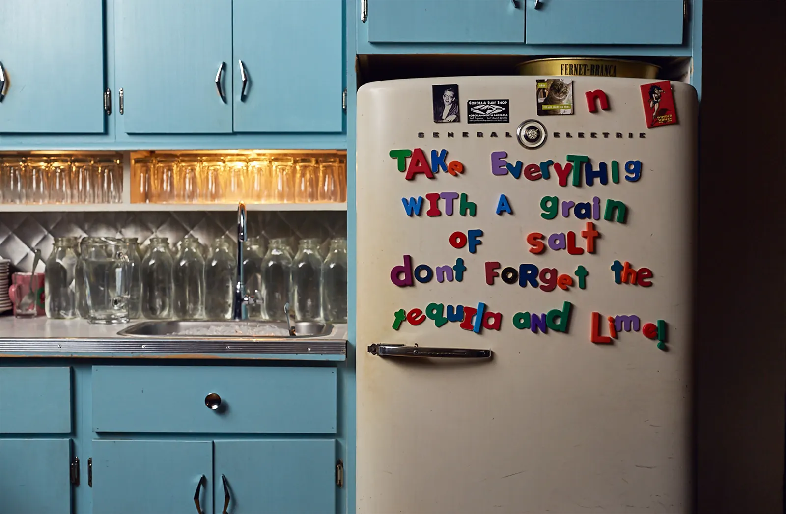 Pale blue cabinets and a fridge covered in magnetic letters.
