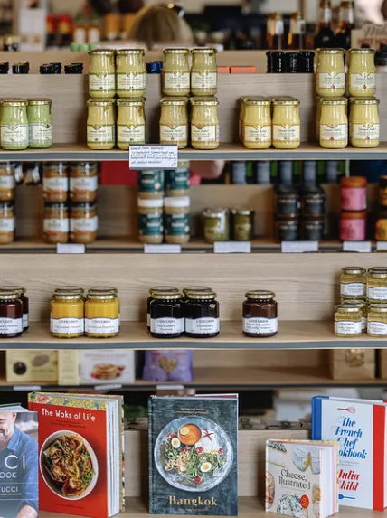 Jars of mustard, jam and preserves above a row of cookbooks.