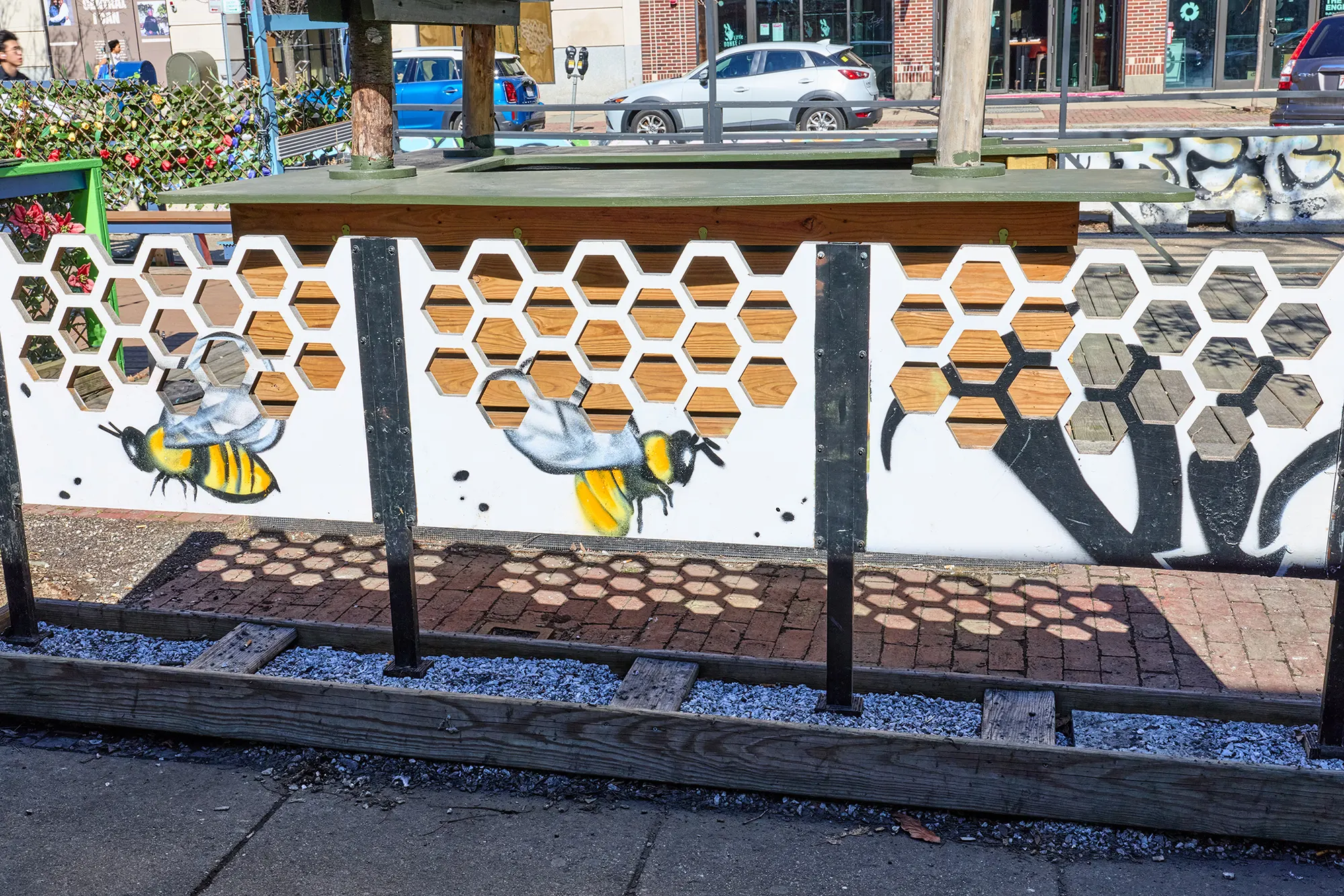Painted bees on white screen panels cut with honeycomb openings.