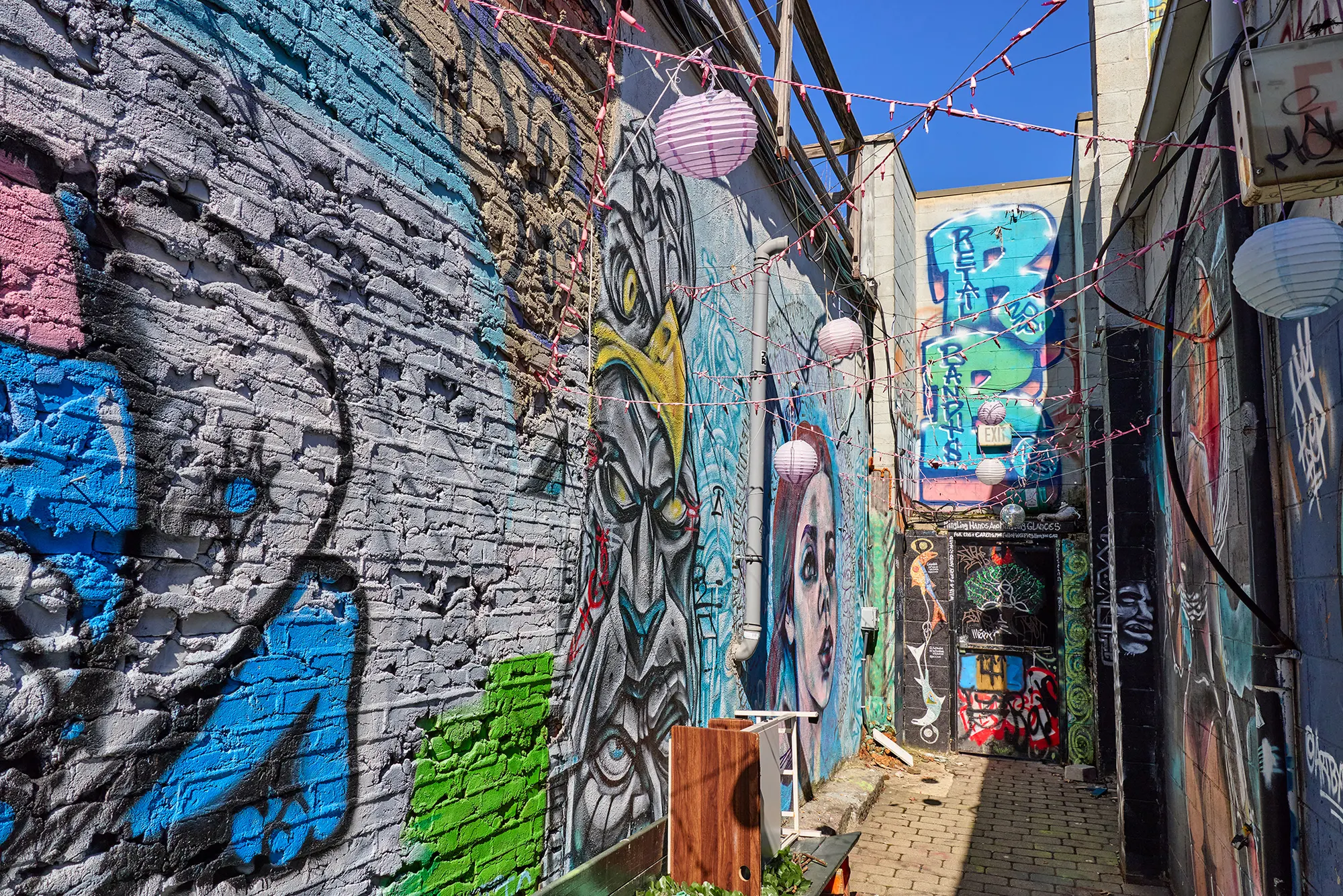 The mural-covered alley with its lanterns, looking toward a painted wall.