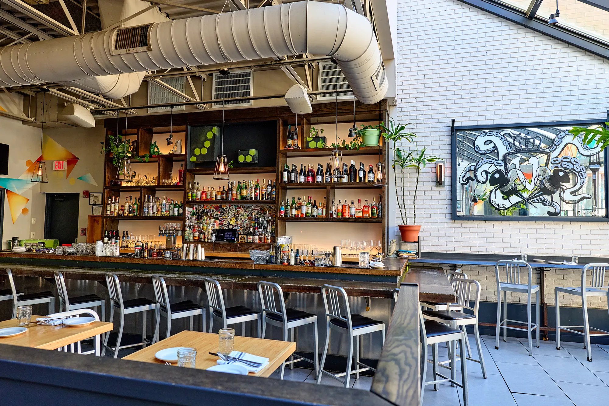 The back bar and dining tables beneath exposed ductwork.