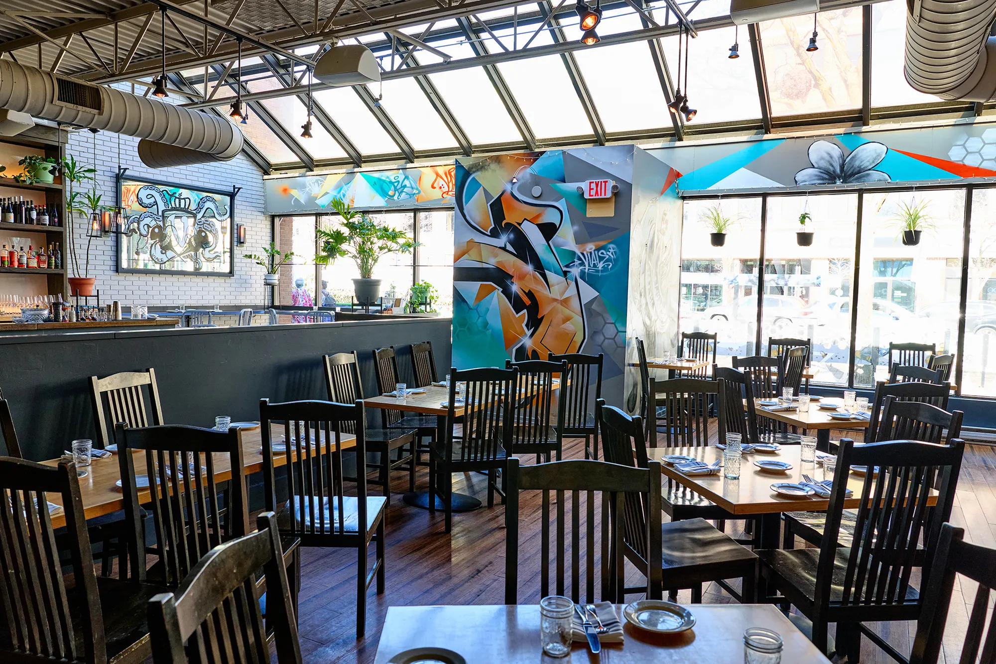 The dining room at Viale under its glass roof, with murals, plants and the bar