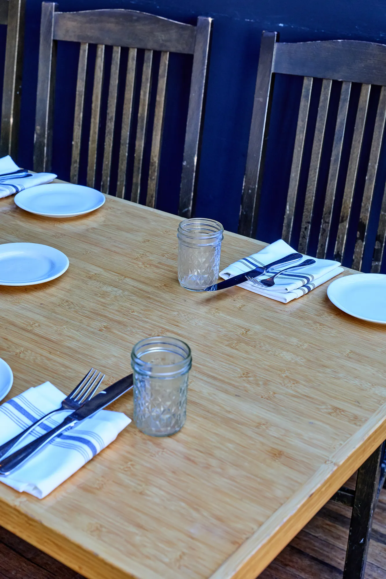 Plates, glasses and napkins on a bamboo table.