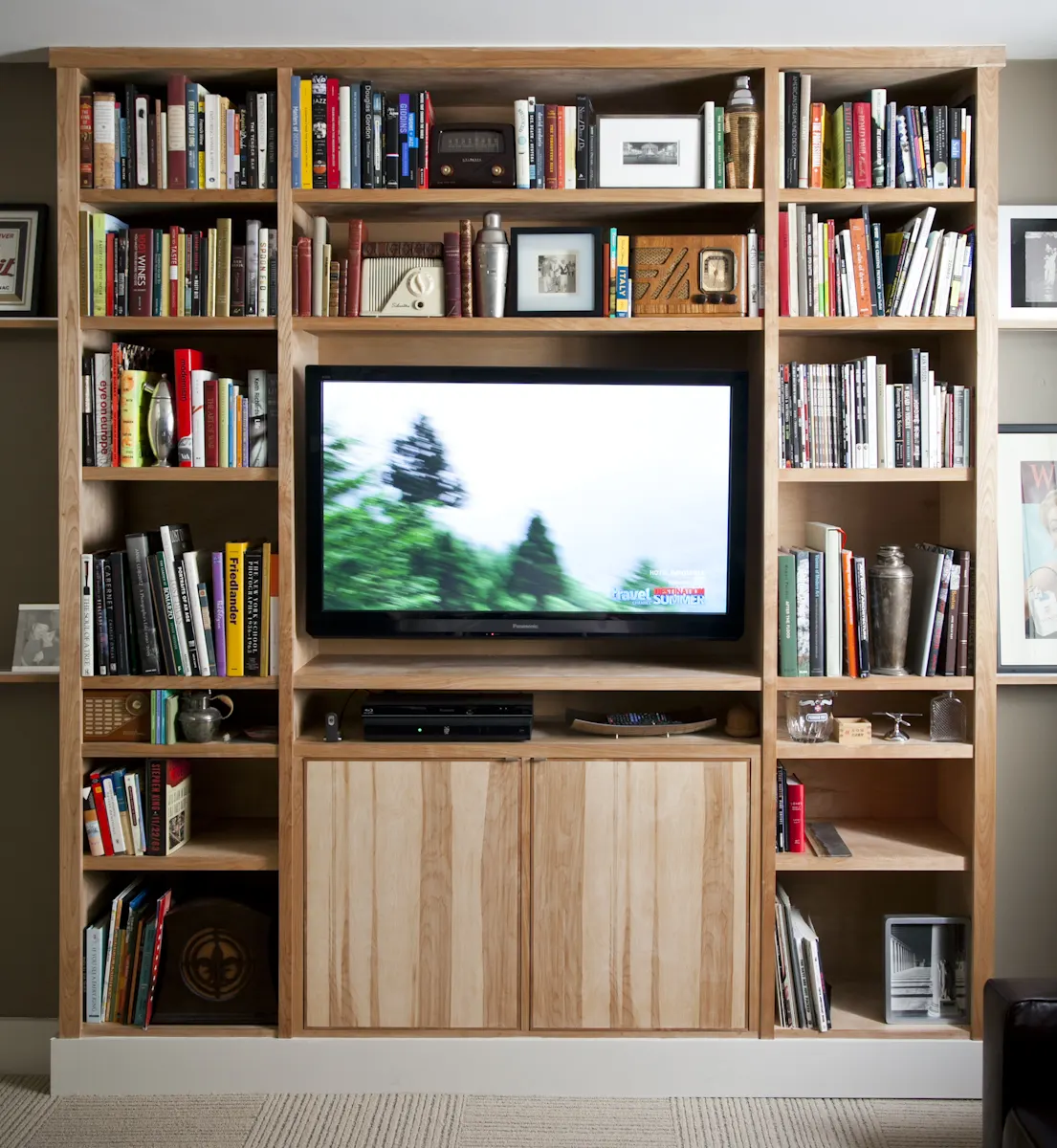 Built-in maple shelves full of books around a television, with cabinets below.