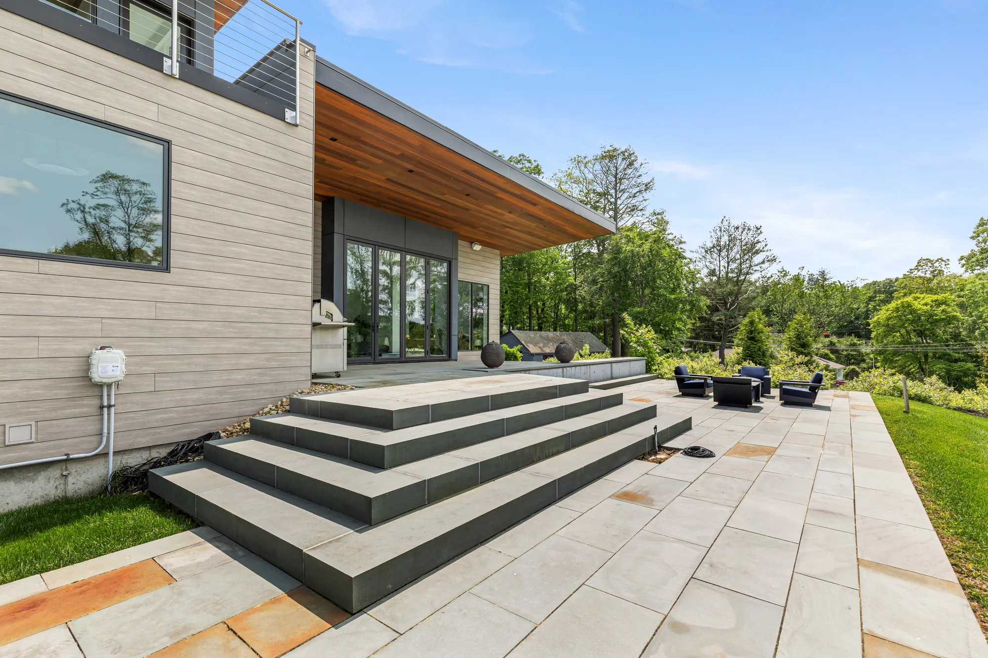 Wide stone steps down to the bluestone terrace, beside the timber-clad wall.