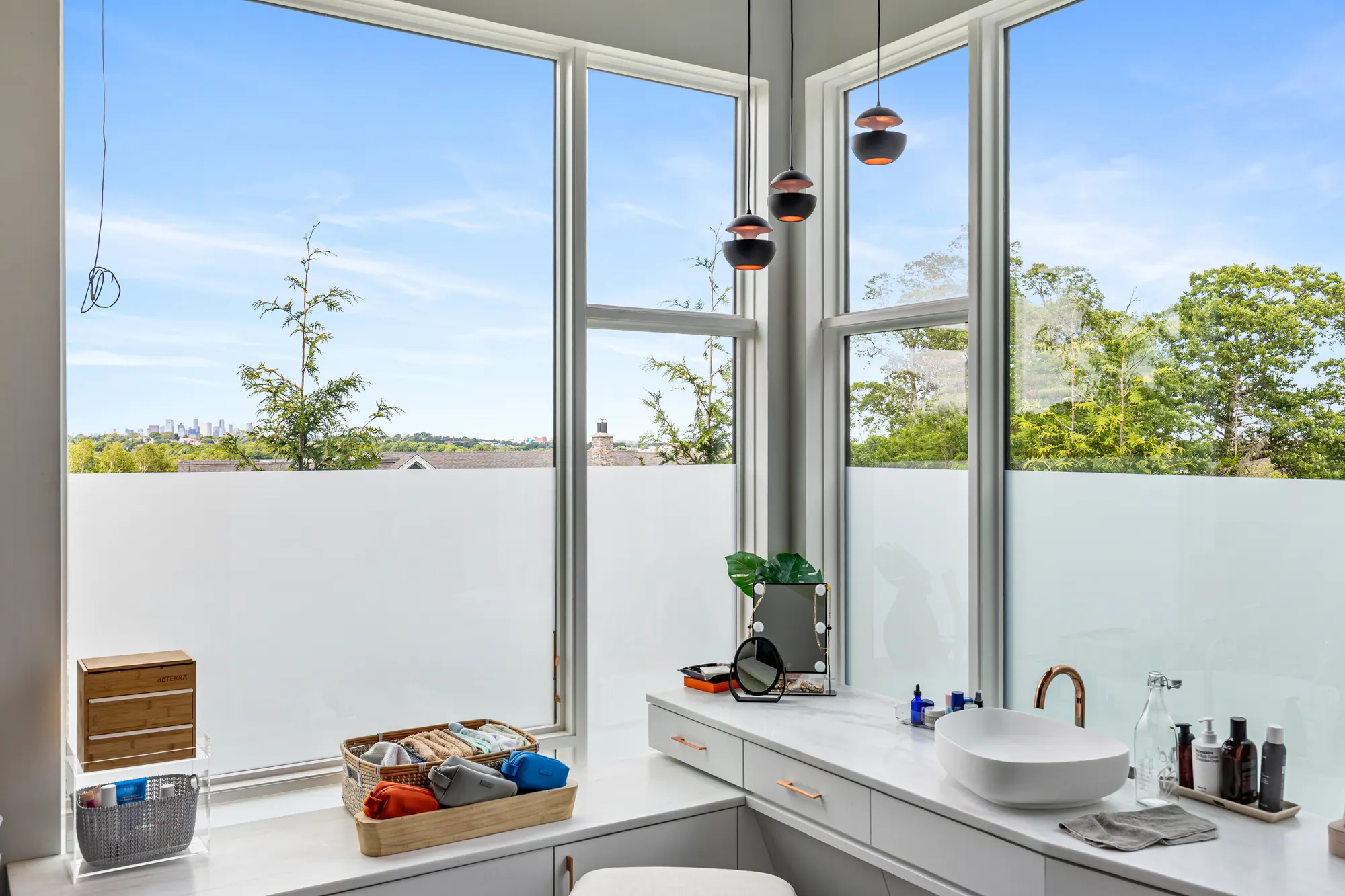 The vanity and basin under the corner windows, the lower panes frosted.