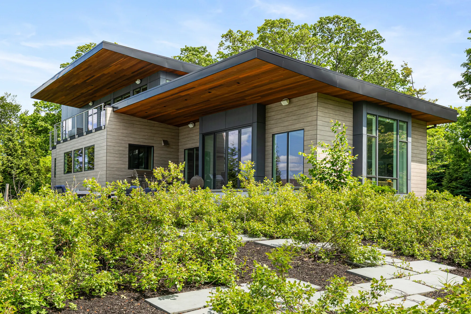 The house across a planted garden crossed by stone stepping slabs.
