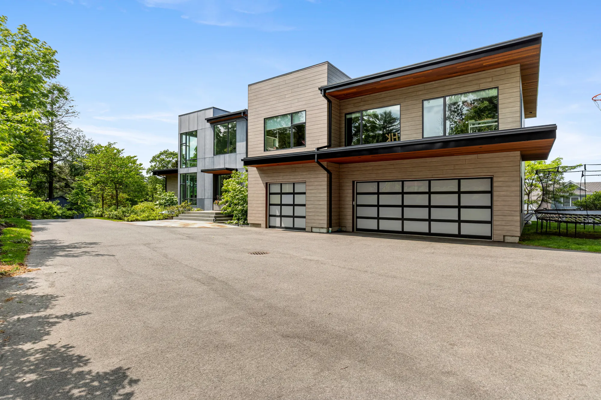 The drive leading to a two-car and a single garage with glazed doors, under an overhanging roof.