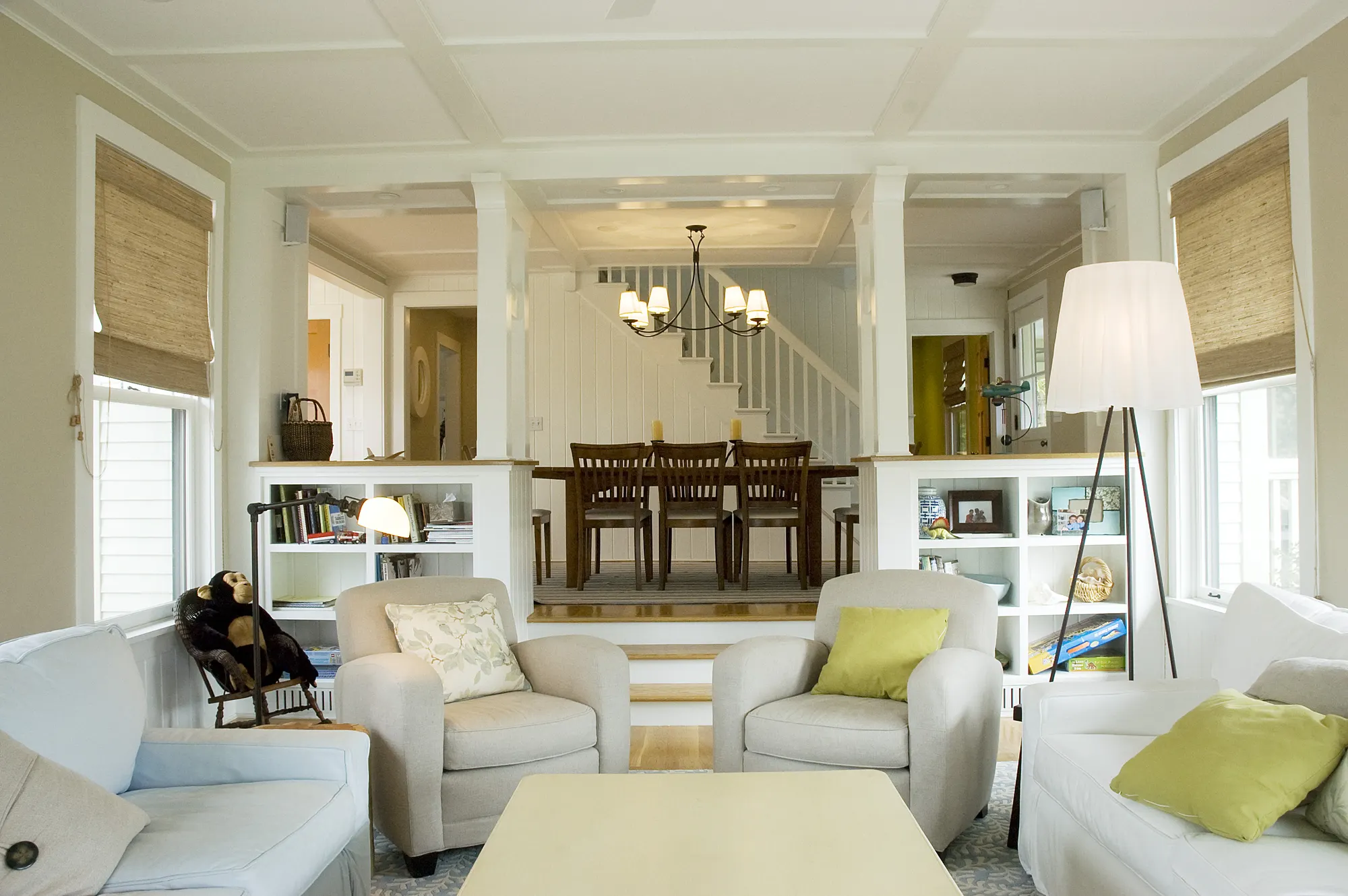 White sofas around a coffee table, with steps up to the dining room beyond.