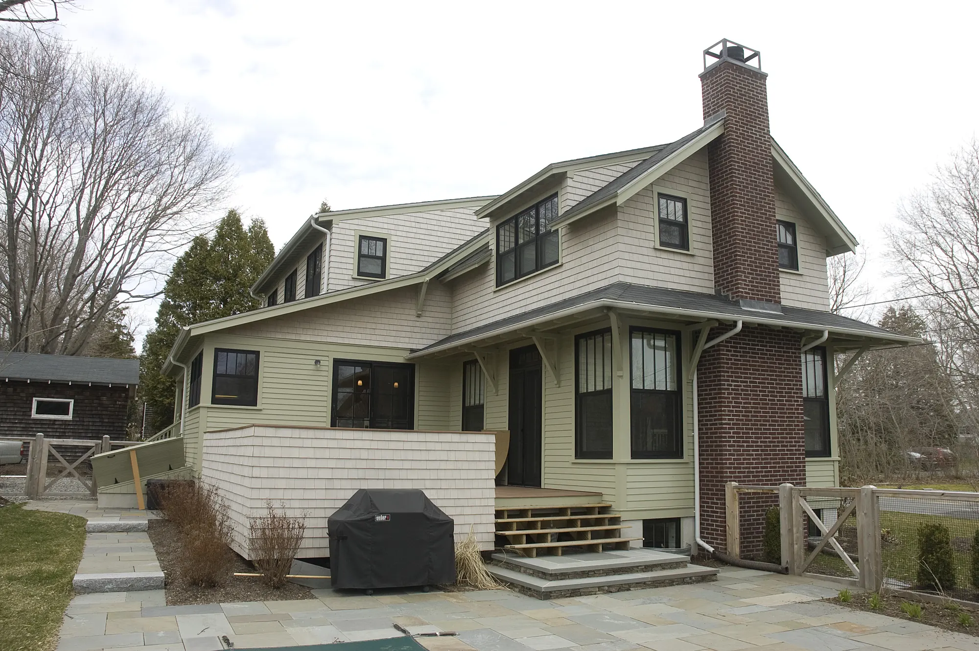 The rear of the house and its brick chimney, with stone steps down to a bluestone terrace.