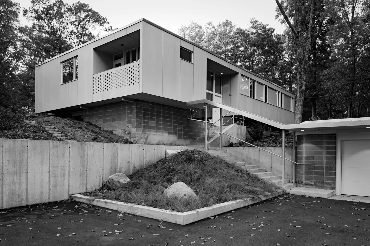 The Lexington Residence, raised on a concrete-block base above the drive, a stair climbing to the entrance