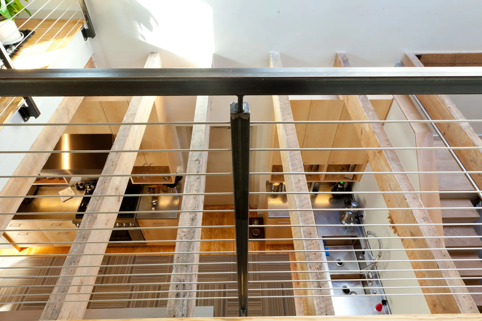 Looking down through a cable balustrade and open treads to the kitchen below.