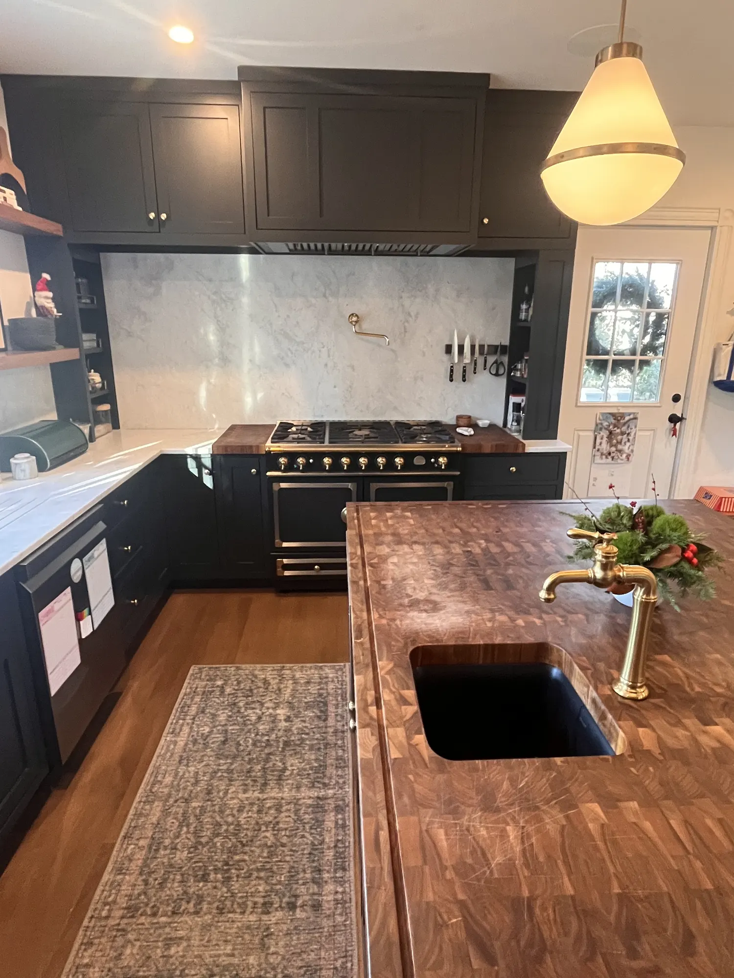 A brass tap over a black sink set into the island's end-grain walnut top.