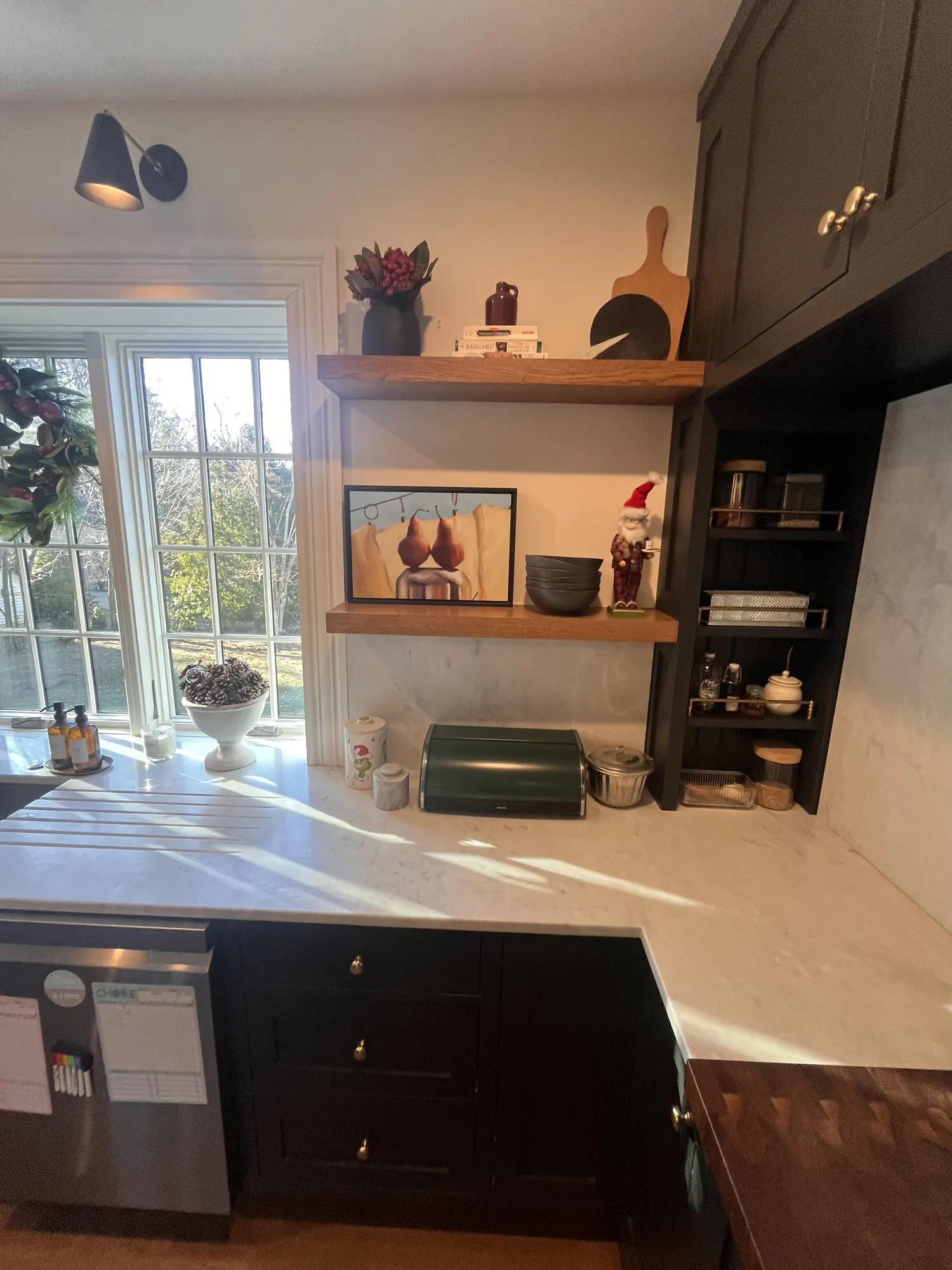 Timber shelves and an open cabinet beside the window, above a marble counter.