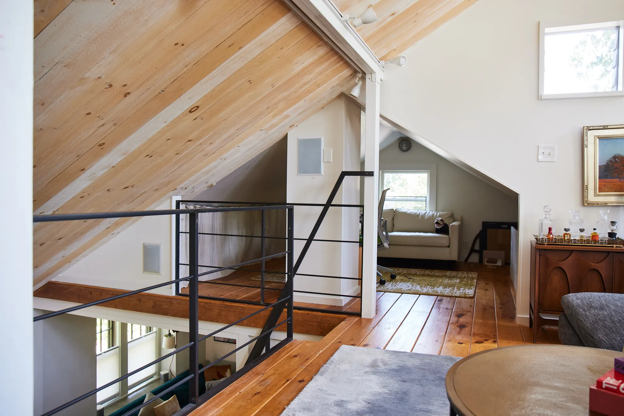 The top of the stair under the pitched ceiling, with a sitting room through the opening beyond.